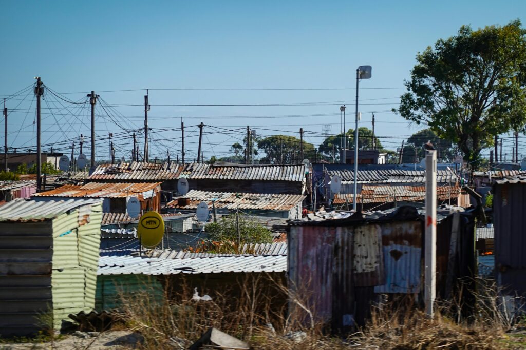 A view of an informal settlement with numerous makeshift rooftops and power lines.