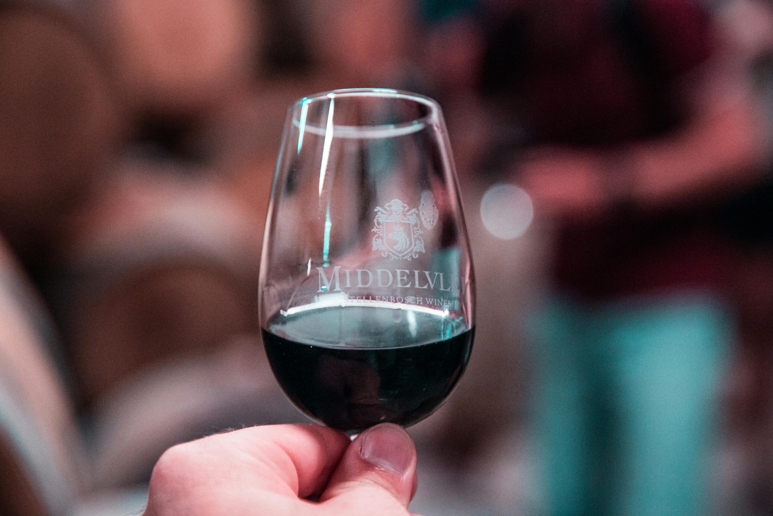 Close-up of a hand holding a glass of red wine at Middelvlei Wine Estate, Stellenbosch.